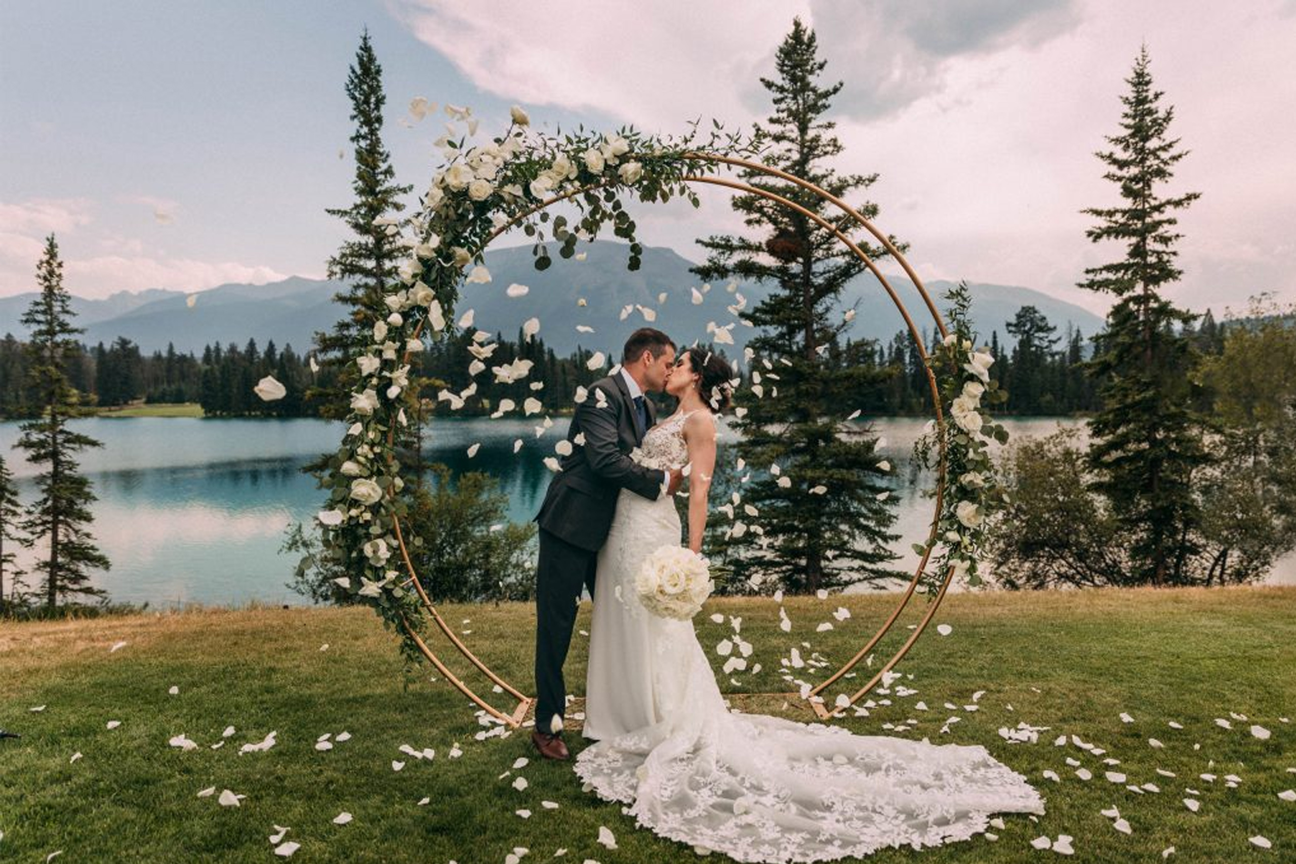 couple kissing in front of lake in Jasper with a shower of flower petals | Jasper Alberta wedding photographer