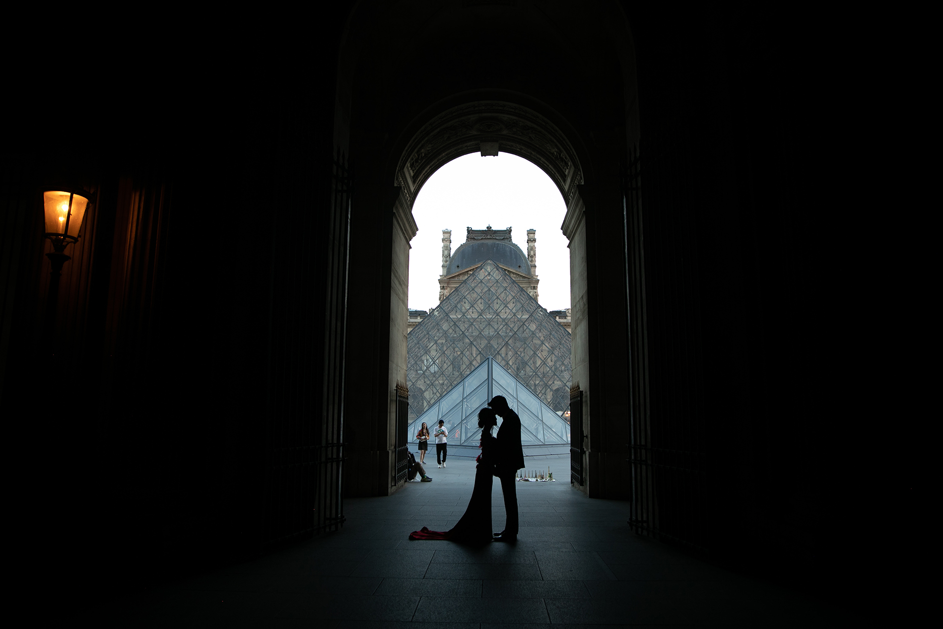 couple standing in the archway of the Louvre museum in Paris